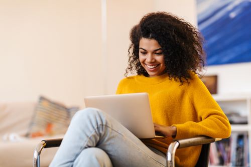Image,of,cheerful,african,american,woman,using,laptop,while,sitting